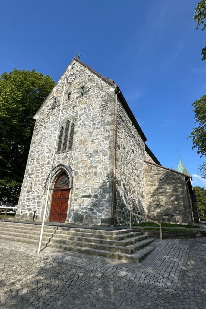 스타방에르 대성당 측면에서 바라본 석조 외관, 고딕 양식 창문과 뾰족 지붕이 조화를 이루는 모습