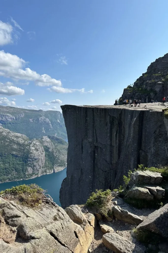 노르웨이 프레이케스톨렌 절벽 정상에 앉거나 서 있는 등산객들, 하단에 펼쳐진 피오르드 전경과 어우러진 장면
