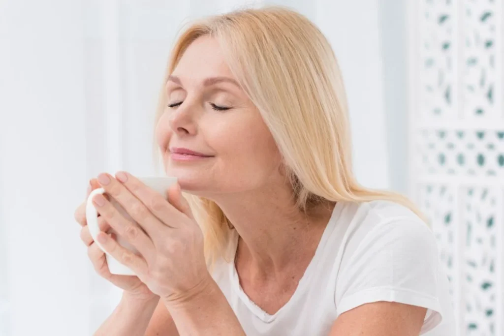 갱년기 호르몬치료 꼭 해야 할까? 장단점과 50대 나의 선택 (미국 병원 후기) 4 갱년기를 맞아 자신을 돌보는 시간을 가지며, 따뜻한 차와 함께 평온한 미소를 짓고 있는 50대 여성