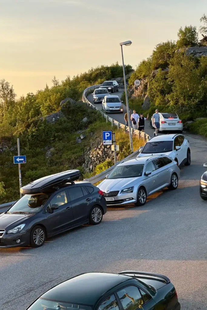 노르웨이 올레순 악슬라 전망대 정상의 좁은 주차 공간으로 진입하기 위해 대기하거나 서행하는 자동차들의 모습. 주차장의 혼잡한 상황을 보여준다.
