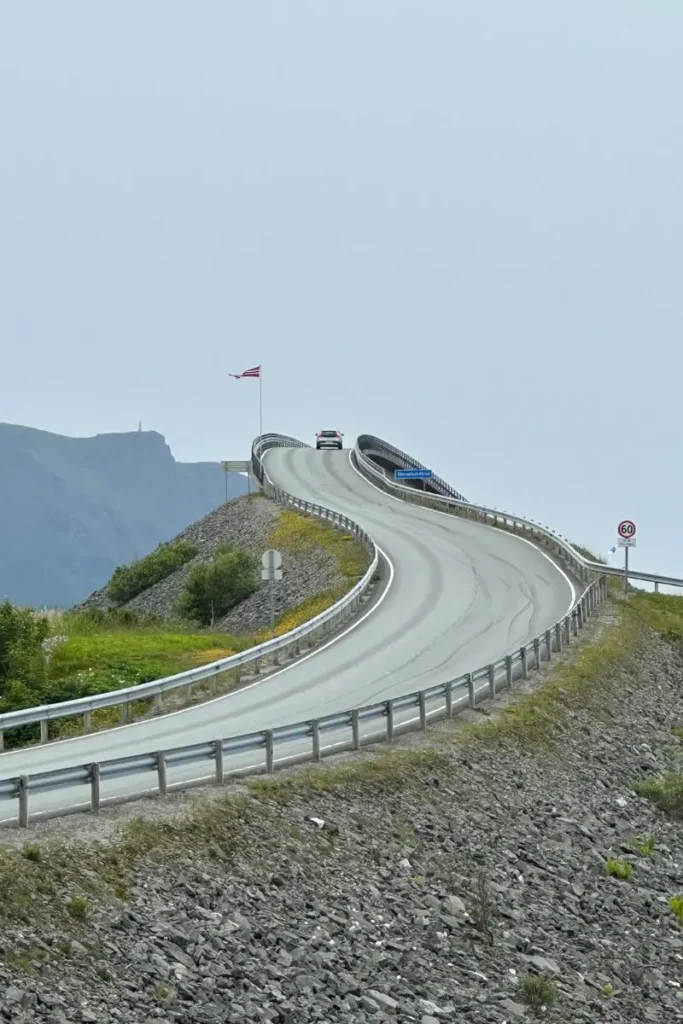 노르웨이 아틀란틱 로드의 스토르세이순데트 다리가 바다 위를 가로지르며 부드럽고 우아한 곡선을 그리고 있는 전경. 파란 하늘과 대비되는 다리의 모습이 인상적이다.